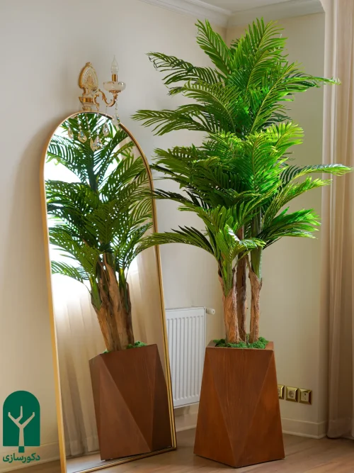 درختچه نخل کنتیا مصنوعی ارتفاع 190 سانتی متر در دکور کلاسیک ایرانی با گلدان هشت ضلعی چوبی قهوه ای 60 سانتیمتر فروشگاه دکورسازی در کنار آیینه چوبی طلایی کلاسیک